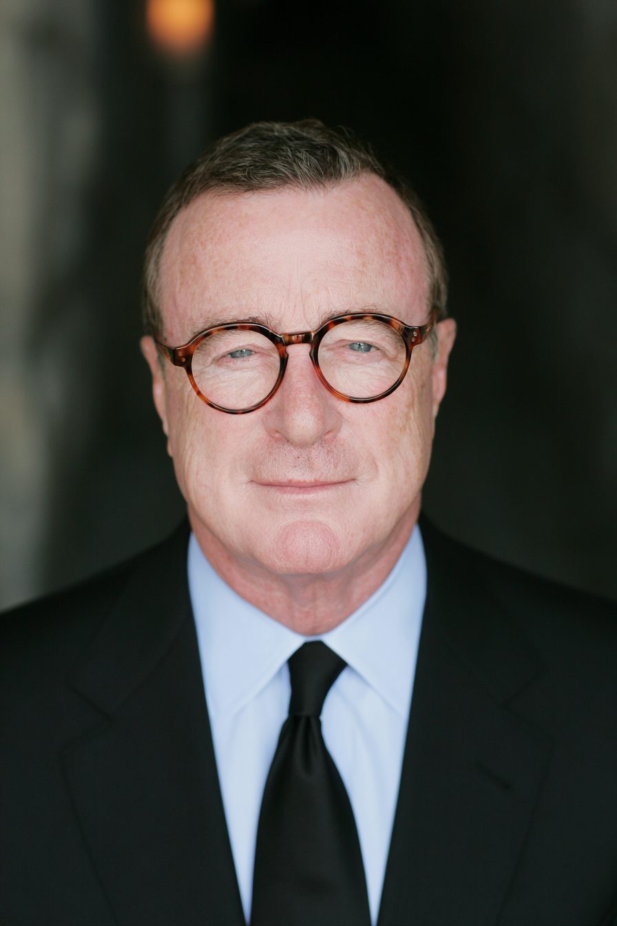 Henry Pell in round tortoiseshell glasses and a dark suit